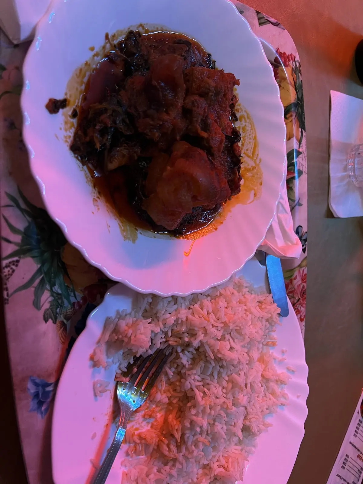 A plate of rice topped with stewed meat and fried plantain, shot from overhead.